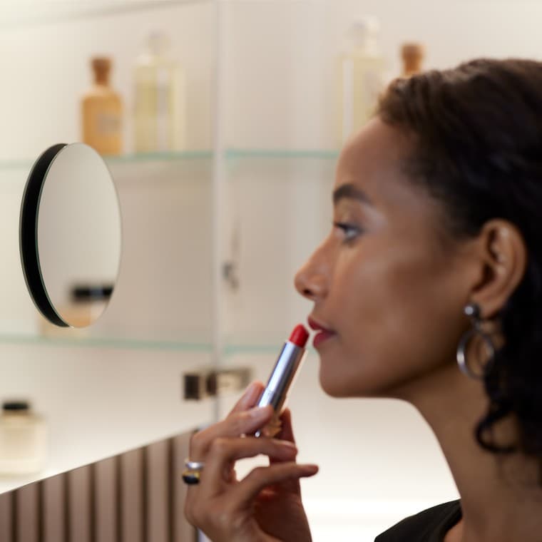 Žena nanášajúca si make-up pri pohľade do zrkadla Žena nanášajúca si make-up pri pohľade do zrkadla